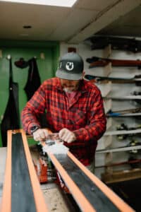 Skilled technician tuning skis in Vista Bahn's workshop, showcasing personalized service and expert maintenance for ski rentals.